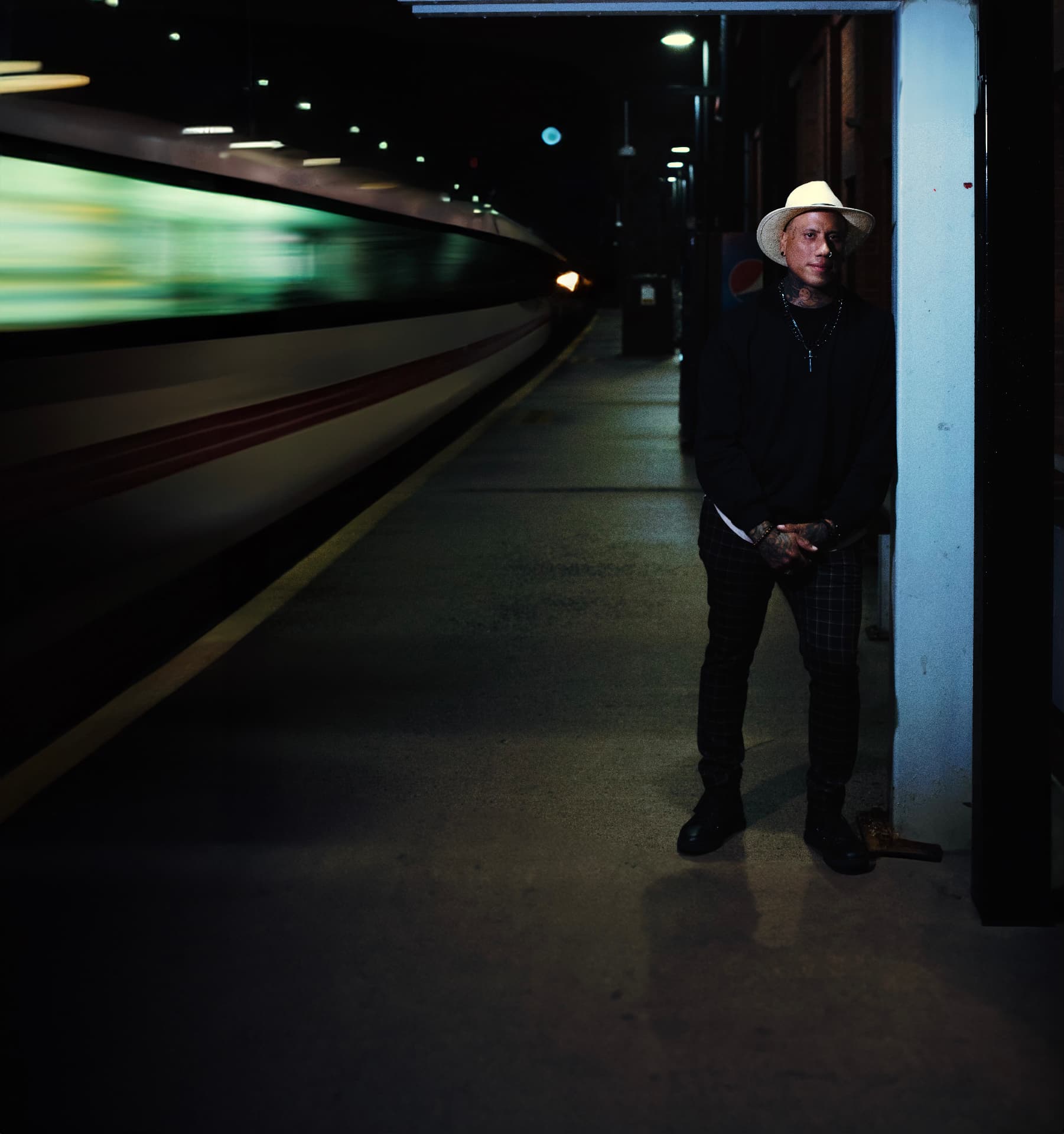 DJ Gruvy waiting on a night platform as a train blurs past